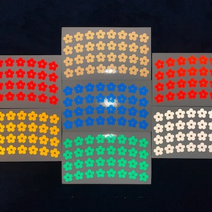 Op de afbeelding: Set van tien vellen met bloemen stickers in verschillende kleuren, waaronder wit, oranje, geel, blauw, groen en rood. Elk vel heeft 36 stickers.