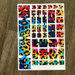 May include: A sheet of colorful keyboard stickers with a leopard print and tie-dye pattern. The stickers are arranged in a grid and are ready to be applied to a keyboard.