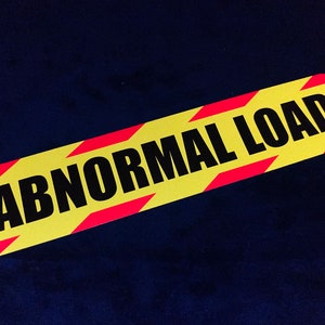 May include: A yellow and red striped sign with the text "ABNORMAL LOAD" in black letters.