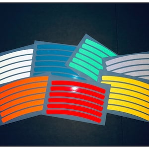 May include: Assortment of reflective wheel rim stickers in various colours, including white, orange, red, yellow, teal, green, and grey. The stickers are designed to enhance visibility and safety while riding.