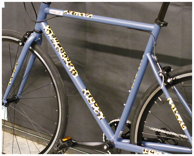 May include: A blue bicycle with leopard print tape on the frame. The bicycle has a black seat and handlebars.