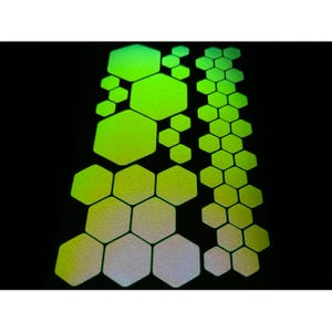 May include: A collection of neon green and white hexagonal shapes against a black background. The shapes vary in size and are arranged in vertical columns and scattered patterns. The design has a reflective, textured appearance.