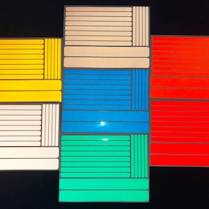 Puede incluir: Surtido de pegatinas reflectantes para radios de bicicleta en varios colores, incluyendo blanco, amarillo, azul, verde, naranja y rojo. Las pegatinas están dispuestas en una cuadrícula.