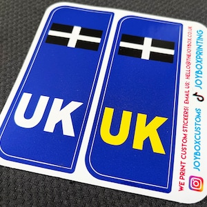 May include: Two blue and white stickers with the text "UK" in white and yellow letters. The stickers also feature a black and white flag with a cross. The text "WE PRINT CUSTOM STICKERS! EMAIL US: HELLO@THEJOYBOX.CO.UK JOYBOXCUSTOMS JOYBOXPRINTING" is printed on the right sticker.