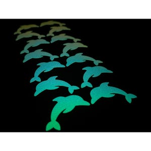May include: A collection of teal and green dolphin-shaped stickers arranged on a black background. The stickers have a gradient effect, transitioning from teal to green. The dolphins are facing in the same direction, creating a sense of movement.