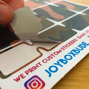 Puede incluir: Una hoja de pegatinas personalizadas con un patr&oacute;n de camuflaje. Las pegatinas tienen forma de bocadillos de di&aacute;logo. El texto en la hoja dice "WE PRINT CUSTOM STICKERS! EMAIL US: HELLO@THEJOYBOXBUDE.COM JOYBOXBUDE"