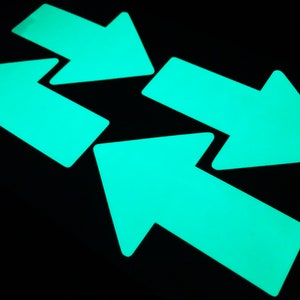 May include: Four bright turquoise glow-in-the-dark arrows pointing in different directions.