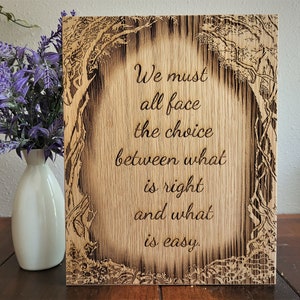May include: A wooden sign with a burnt wood design of trees and the quote "We must all face the choice between what is right and what is easy."