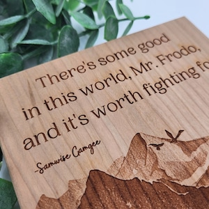 May include: Wooden sign with a mountain scene and the quote "There's some good in this world, Mr. Frodo, and it's worth fighting for." -Samwise Gamgee