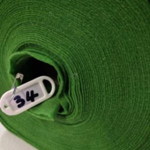 Könnte beinhalten: Eine Rolle grüner Filzstoff mit einem weißen Etikett mit der Aufschrift "34".
