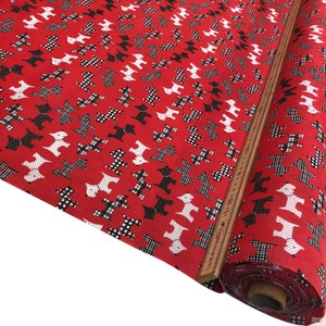 May include: Red fabric with a repeating pattern of black and white dogs. The fabric is rolled up and a measuring tape is visible.