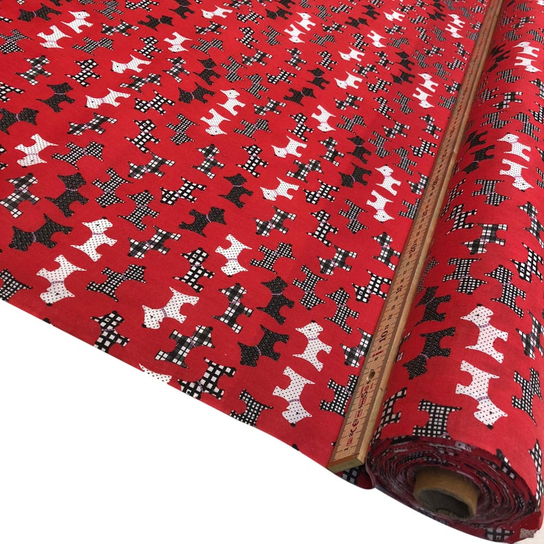 May include: Red fabric with a repeating pattern of black and white dogs. The fabric is rolled up and a measuring tape is visible.