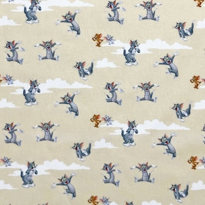 May include: A tan fabric with a repeating pattern of Tom and Jerry cartoon characters. The design features gray cats (Tom) in various poses and brown mice (Jerry). White cloud shapes are interspersed throughout the pattern.