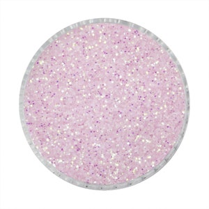 Op de afbeelding: Een cirkelvormige container gevuld met lichtroze glitter. De glitter heeft een sprankelende, iriserende kwaliteit, met witte en paarse vlekken. De container heeft een heldere, transparante rand.