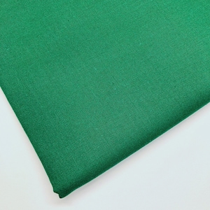 May include: A close-up of a solid green fabric. The fabric has a smooth, even texture.