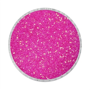 Op de afbeelding: Een ronde container gevuld met levendige roze glitter. De glitter heeft een sprankelende, iriserende kwaliteit, met kleine gouden vlekjes. De container heeft een zilveren rand en staat tegen een witte achtergrond.