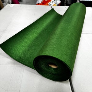 Puede incluir: Un rollo de tela de fieltro verde. La tela est&aacute; enrollada y el extremo est&aacute; doblado. La tela es de color verde oscuro.