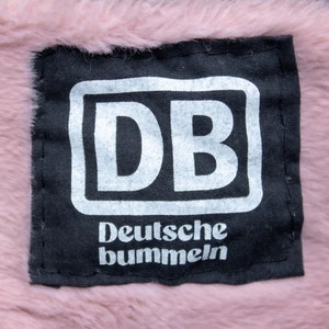Könnte beinhalten: Schwarzer Patch mit weißem Text, der "DB Deutsche bummeln" lautet.