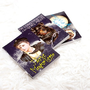 May include: A stack of three art prints with celestial and portrait designs. One print features a young man with the text "I love Major Tom". Another print shows a dog with the text "I'm constantly thinking about you". The third print has a moon and bird.