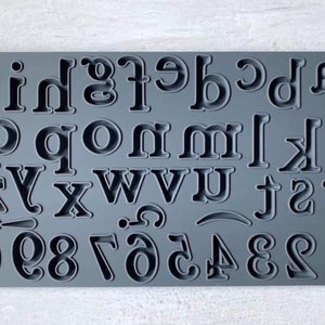 May include: A gray silicone alphabet and number mold with raised letters and numbers. The mold includes the letters A through Z and the numbers 0 through 9.