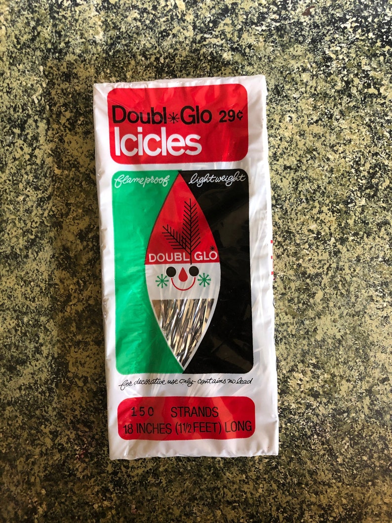 May include: A package of vintage "Doubl Glo Icicles" Christmas decorations. The white package has red, green, and black accents with text that reads "flameproof" and "lightweight". The package contains 150 strands, each 18 inches long.
