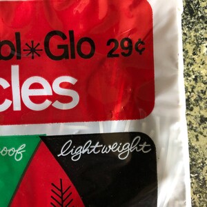 May include: Close-up of a package with red and black labels. The red label reads "Glo" with a star symbol and "29&cent;". The black label says "lightweight" in cursive. The package is white.