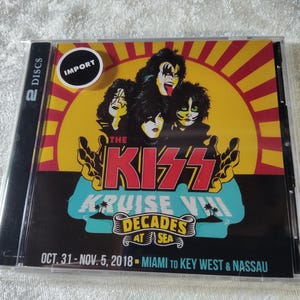 May include: A CD case featuring the band KISS. The cover art includes illustrations of the band members with makeup, the text "THE KISS KRUISE VIII DECADES AT SEA", and the dates "OCT. 31-NOV. 5, 2018". The case has a sticker that says "IMPORT".
