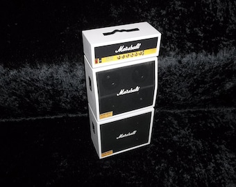 May include: A stack of three white and black Marshall guitar amplifiers. The top amplifier has a yellow label with the text "Marshall" and the text "JCM 800 2203". The middle amplifier has a black label with the text "Marshall" and the text "JCM 800 LEAD 1987". The bottom amplifier has a black label with the text "Marshall" and the text "JCM 800 LEAD 1987".