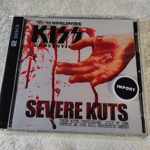 May include: A CD case for the KISS Convention, titled "Severe Kuts." The cover art features a hand with blood dripping down. The CD case is labeled "2 DISCS" and includes the text "Deep Kuts Unplugged - July 27 1995, Detroit, MI COBO Hall Exhibition Center."