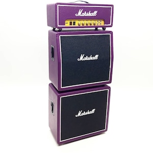 May include: A stack of purple Marshall guitar amplifier equipment. The top unit is a head with knobs and the Marshall logo. The middle and bottom units are speaker cabinets with black speaker covers and the Marshall logo.