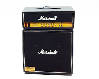 May include: Black Marshall JCM 800 Lead Series guitar amplifier head and cabinet. The head has a black faceplate with a gold trim and the Marshall logo in white. The cabinet has a black faceplate with a gold trim and the Marshall logo in white. The cabinet has a black speaker grill.