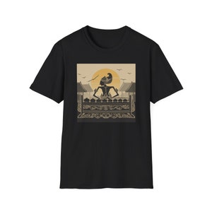 May include: Black t-shirt featuring a graphic print of a silhouette of a person playing a traditional Indonesian musical instrument, the gamelan, against a backdrop of a sunset and a temple.