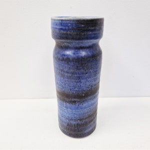 May include: A blue and black ceramic vase with a textured finish. The vase has a cylindrical shape with a slightly wider opening at the top.