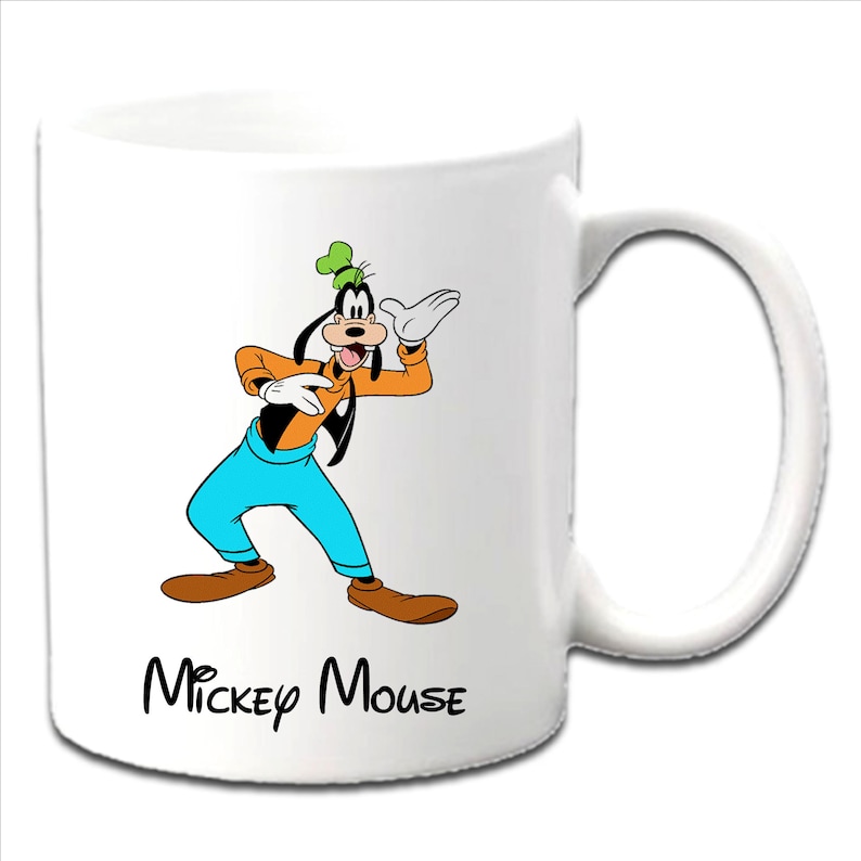 May include: White ceramic mug featuring a colorful illustration of Goofy from Disney's Mickey Mouse. Goofy is depicted in his signature orange shirt, blue pants, and green hat. The words "Mickey Mouse" are printed in black script below the character.