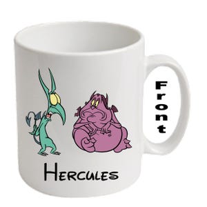 May include: White ceramic mug with cartoon characters from the film Hercules. The mug features a green character with yellow eyes and a purple character. The word "Hercules" is printed at the bottom.