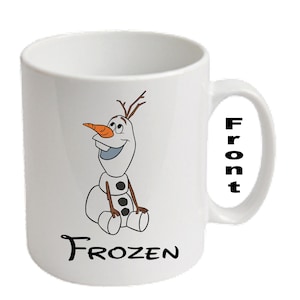 May include: White ceramic mug with a cartoon image of Olaf from Frozen. The design shows Olaf's face, body, and the word "FROZEN" in black. The word "Front" is printed on the handle.