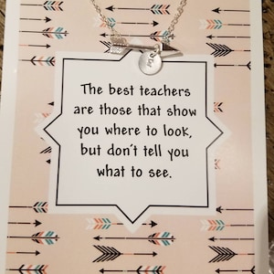 May include: A card with a pink background and a white speech bubble with the text "The best teachers are those that show you where to look, but don't tell you what to see."  The card has a silver arrow necklace with a small round charm.