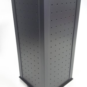 May include: Black rotating display stand with a grid of holes for displaying earrings or other small jewelry. The stand has a square base and is made of a sturdy material.