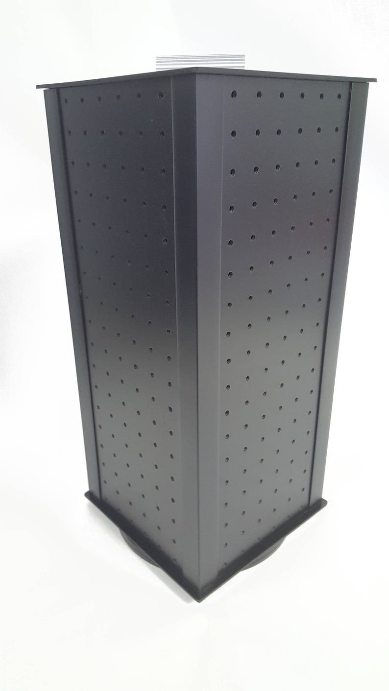 May include: Black rotating display stand with a grid of holes for displaying earrings or other small jewelry. The stand has a square base and is made of a sturdy material.