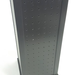 May include: Black rotating display stand with a grid of holes for displaying small items. The stand has a black base and a black top.