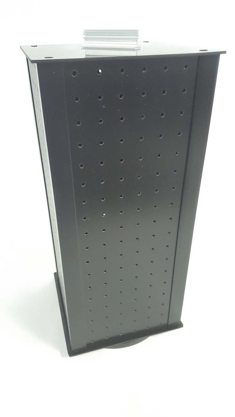 May include: Black rotating display stand with a grid of holes for displaying small items. The stand has a black base and a black top.