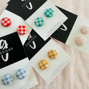 Puede incluir: Surtido de pendientes con estampado de cuadros vichy en varios colores, incluyendo rojo, verde, azul, amarillo y rosa. Los pendientes se muestran en tarjetas blancas con el texto "Handmade in Brisbane GDESIGNSJEWELLERY.COM.AU".
