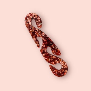 May include: A red glitter mask extender with two loops. The extender is made of plastic and has a sparkly finish.