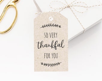 May include: A brown gift tag with the text "So very thankful for you" in black script font. The tag is decorated with small black leaf designs at the top and bottom.