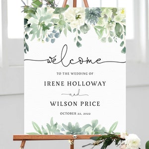 May include: A white wedding welcome sign with floral accents. The sign features the word "welcome" in elegant script, along with the names Irene Holloway and Wilson Price, and the date October 22, 2022. The sign is displayed on a wooden easel.
