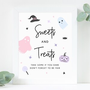 May include: A framed white sign with the words "Sweets and Treats" in black script, decorated with cartoon ghosts, a witch's hat, a pumpkin, and stars. The sign includes the text "Take some if you dare, don't forget to be fair."