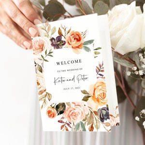 May include: A white wedding welcome sign with a floral border. The sign says "Welcome to the wedding of Katie and Peter July 17, 2021".