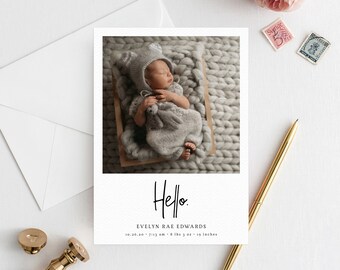 May include: A newborn baby wearing a gray knit outfit and hat, lying in a wooden cradle. The image is on a white card with the word "Hello" in script. The card also includes the baby's name, birth date, time, weight (8 lbs 3 oz), and length (19 inches).