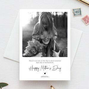 May include: A black and white photograph of a mother and daughter. The daughter is on the mother's shoulders, covering her eyes with her hands. The photo is on a card with the text "There is no role in life that is more essential than that of motherhood. Happy Mother's Day. CRYSTAL"
