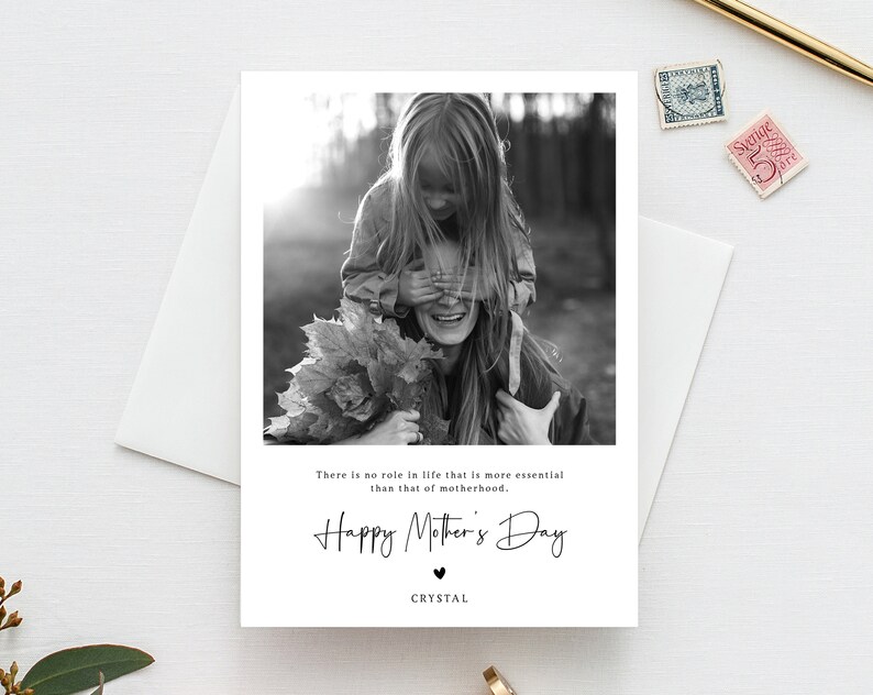 May include: A black and white photograph of a mother and daughter. The daughter is on the mother's shoulders, covering her eyes with her hands. The photo is on a card with the text "There is no role in life that is more essential than that of motherhood. Happy Mother's Day. CRYSTAL"